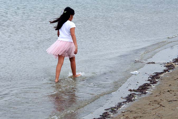 A girl taking a stroll along the beach on her own in Cesenatico, Italy