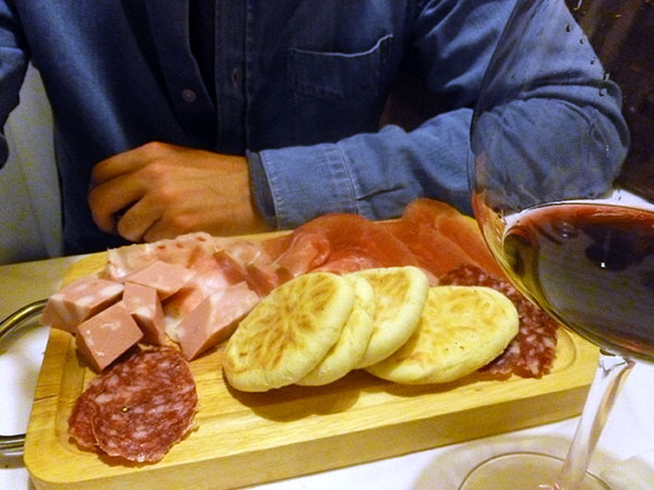 Tigelle and meat on a platter, typical of Bologna cuisine.